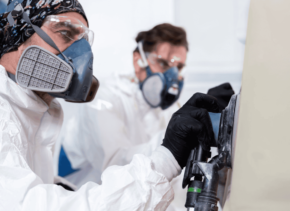 Two technicians wearing personal protective equipment preparing for coating application