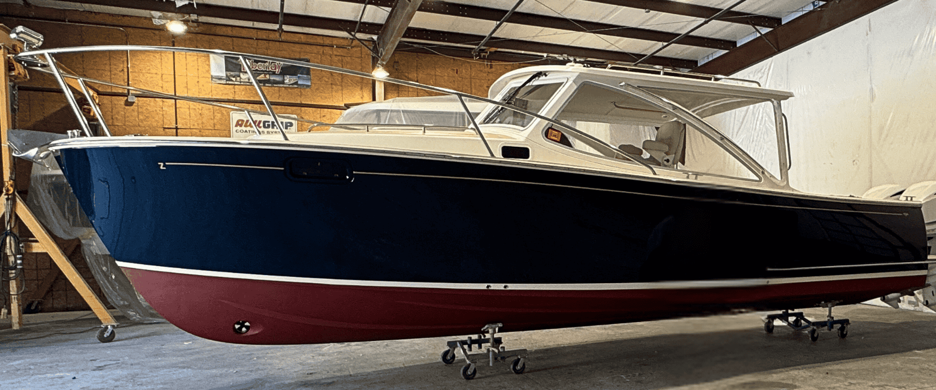 A Metan Marine–restored yacht with a deep blue Awlgrip hull and red antifouling finish inside the company’s Massachusetts workshop.